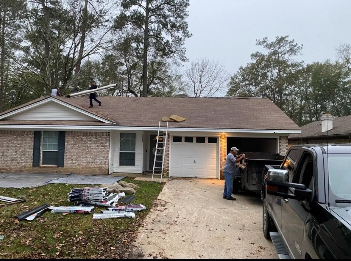 Roofer on a brick house roof with a pickup in the driveway