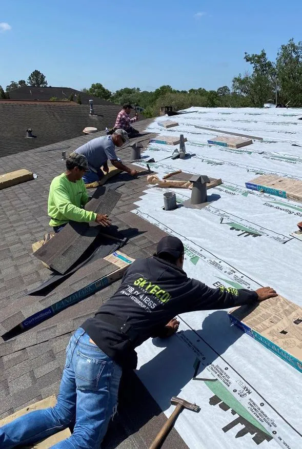 Three roofers laying underlayment and shingles
